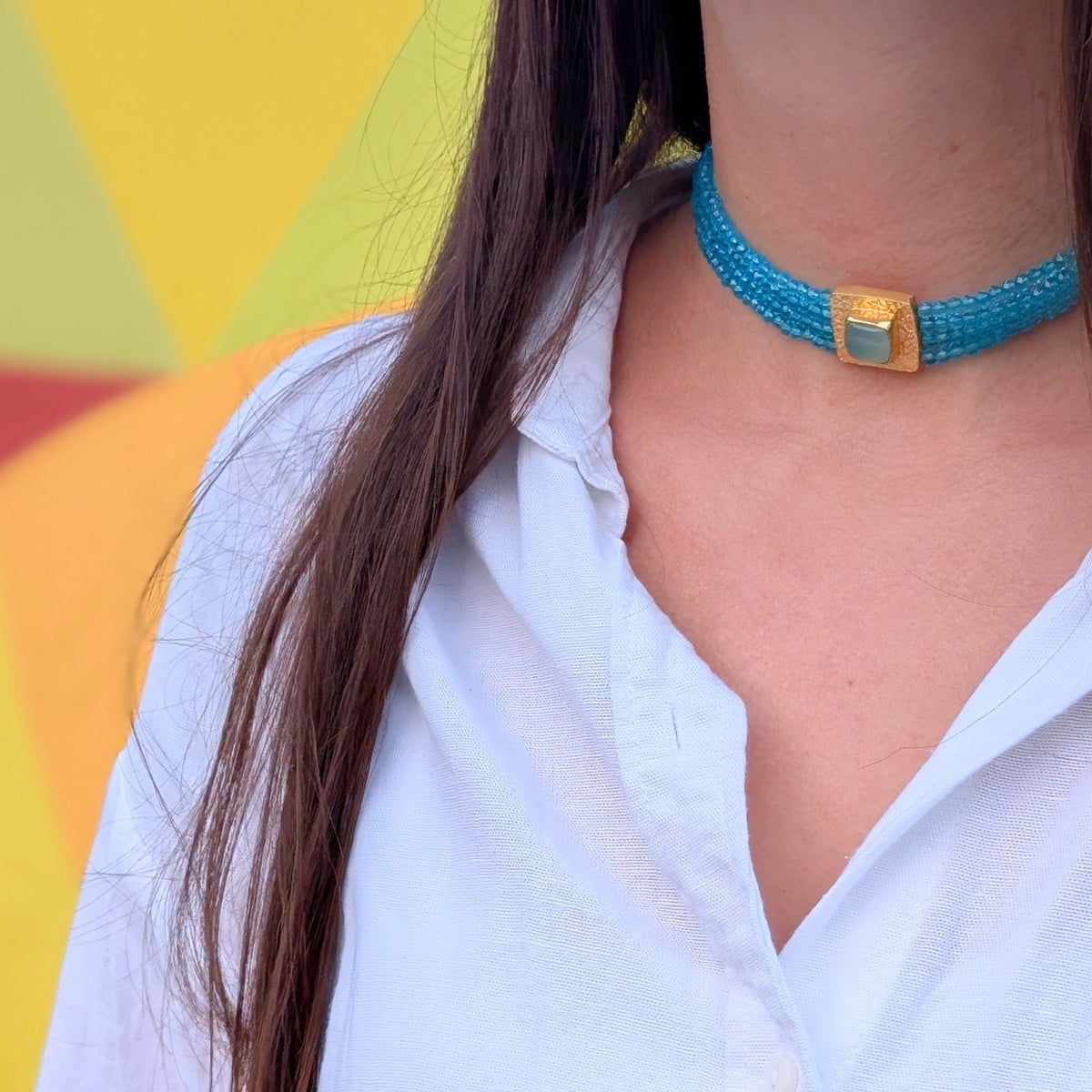 Detalle lateral del choker de cuentas turquesa con placa dorada texturizada de AMANAI