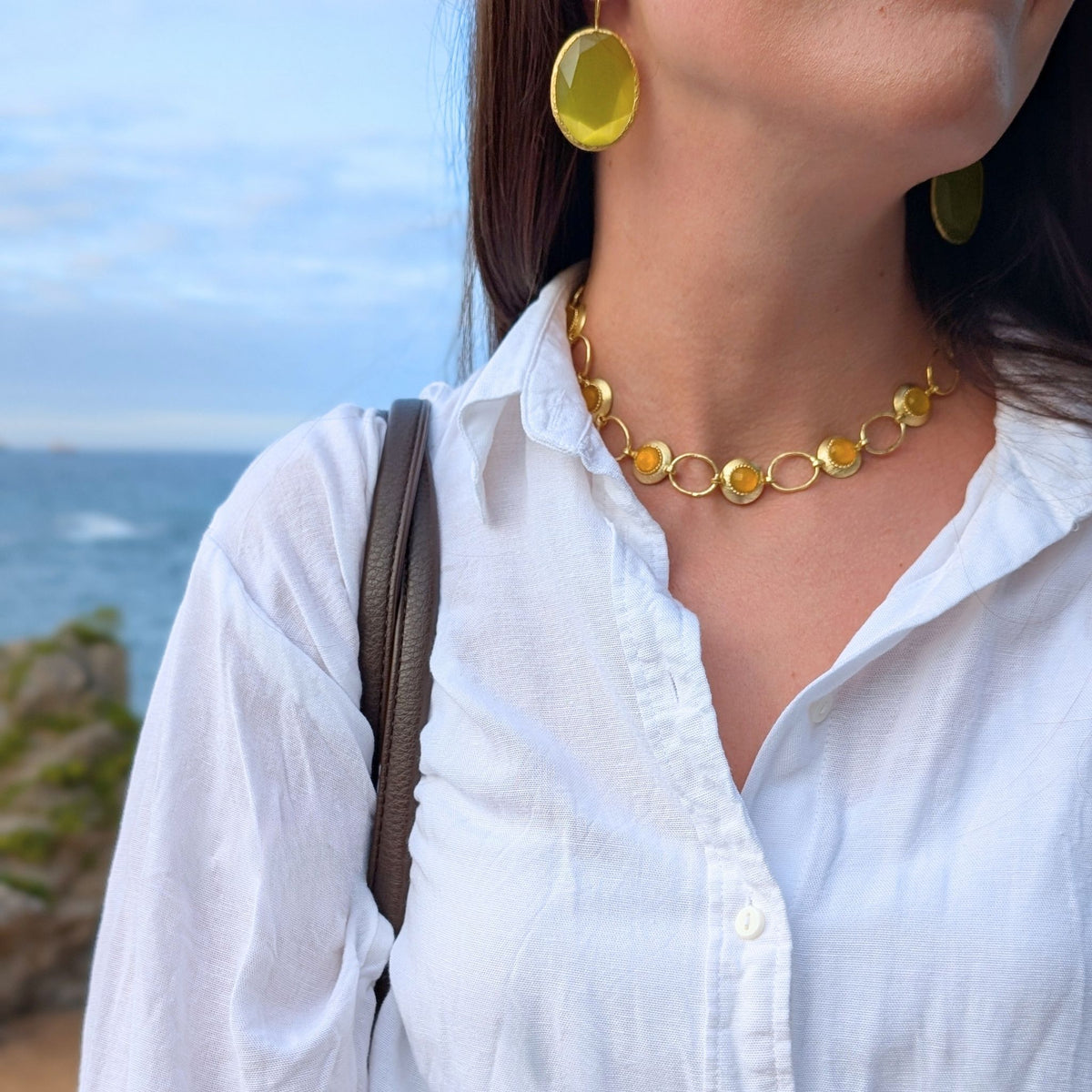 Collar Ámbar de AMANAI con piedras naturales ámbar y eslabones dorados, frente al mar Cantábrico