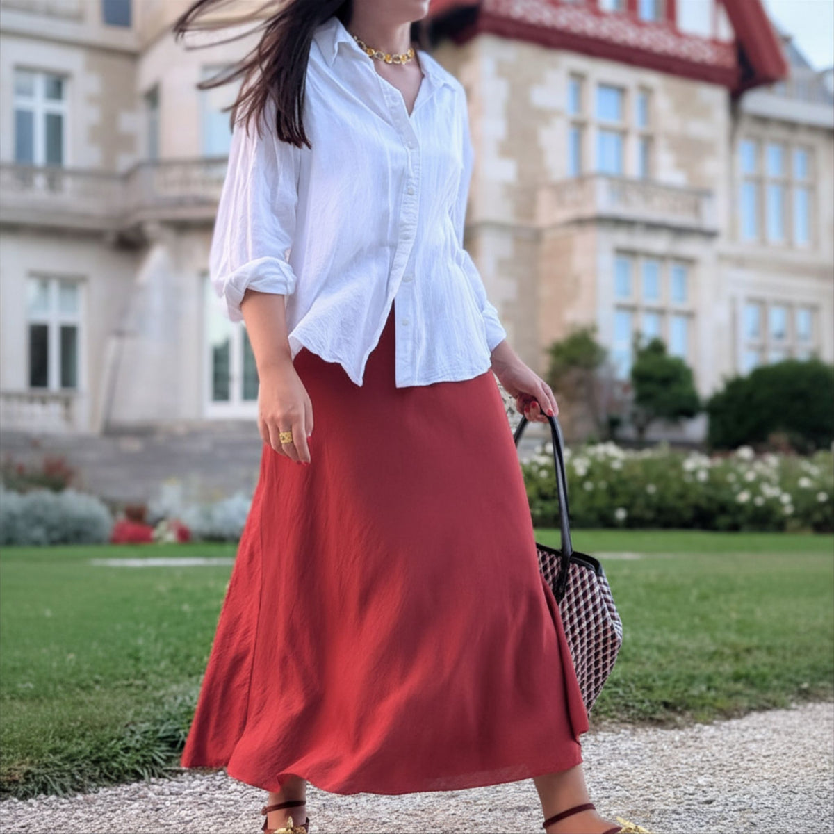 Look Old Money con collar Ámbar dorado de AMANAI, camisa blanca y falda teja en los jardines de la Magdalena