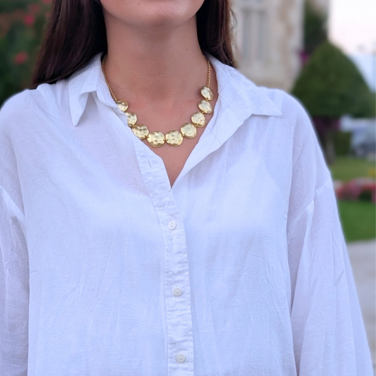 Collar de discos dorados martillados de AMANAI bañado en oro de 18 quilates sobre camisa blanca