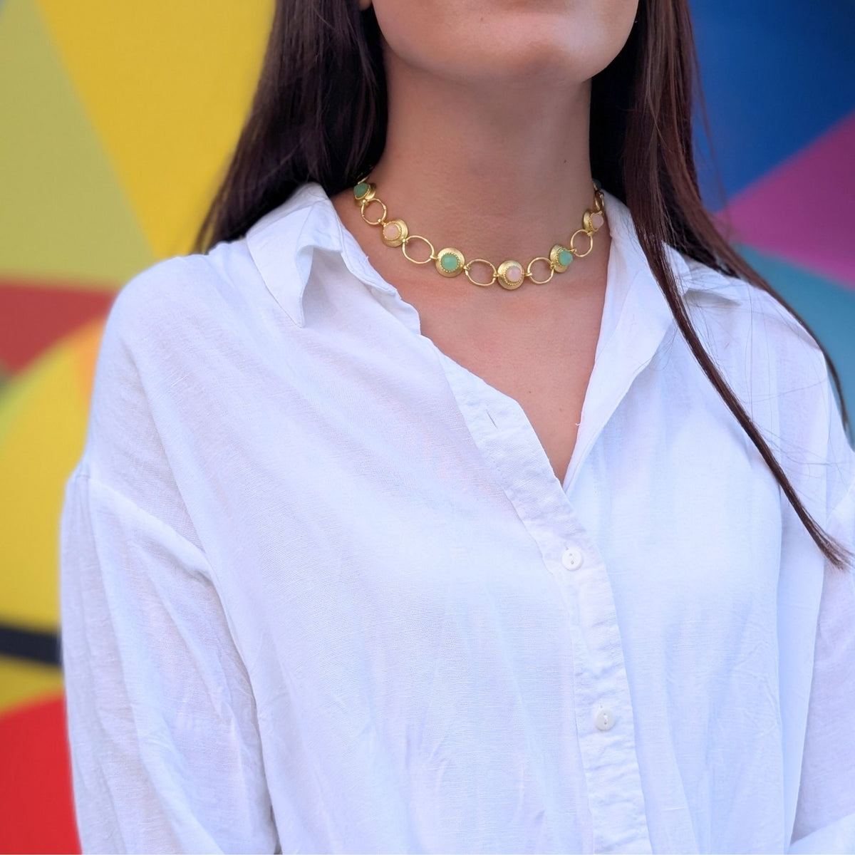 Collar Marea de AMANAI con eslabones dorados y piedras naturales verdes y rosas sobre camisa blanca