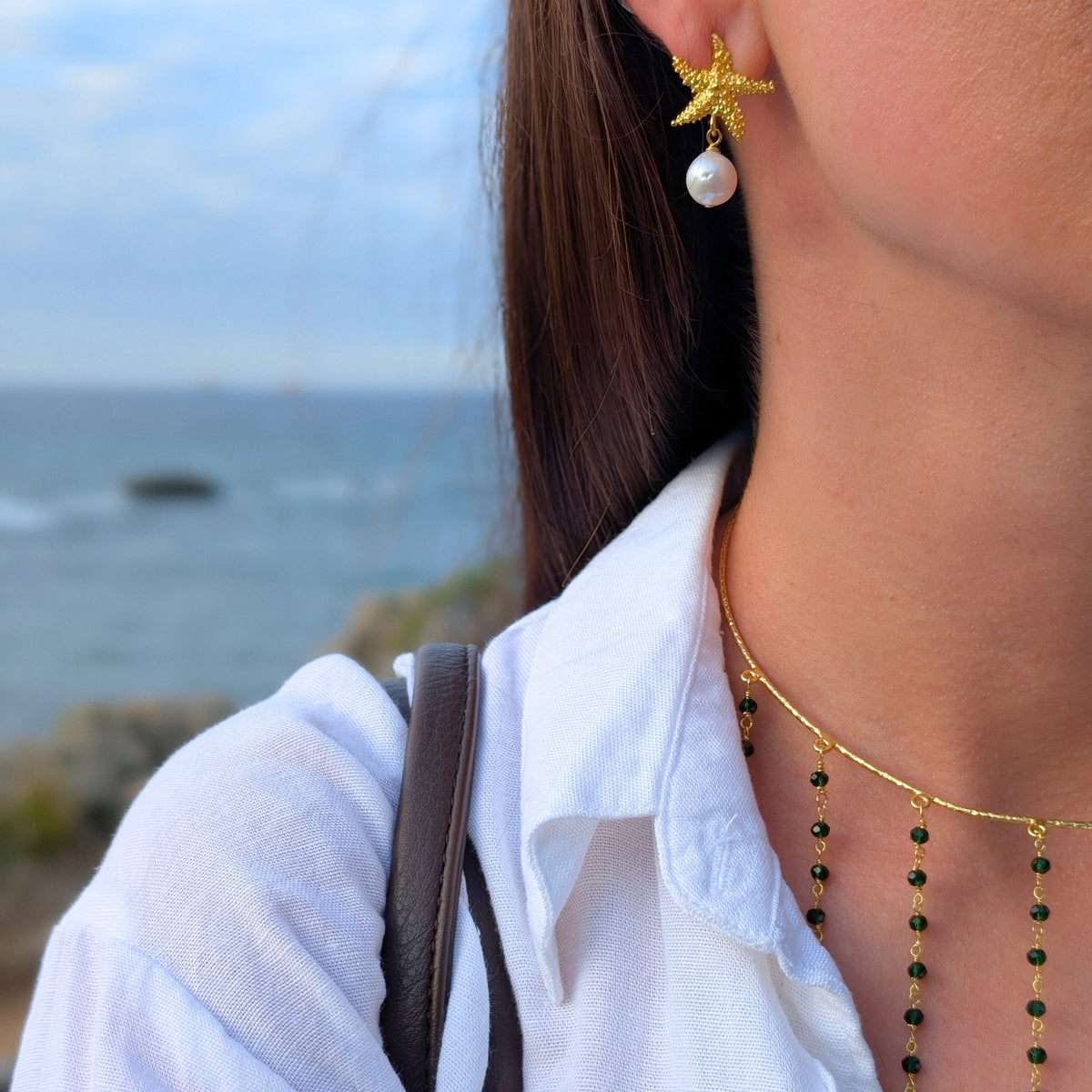 Pendientes Ariel de estrella de mar con perla de AMANAI frente al mar Cantábrico