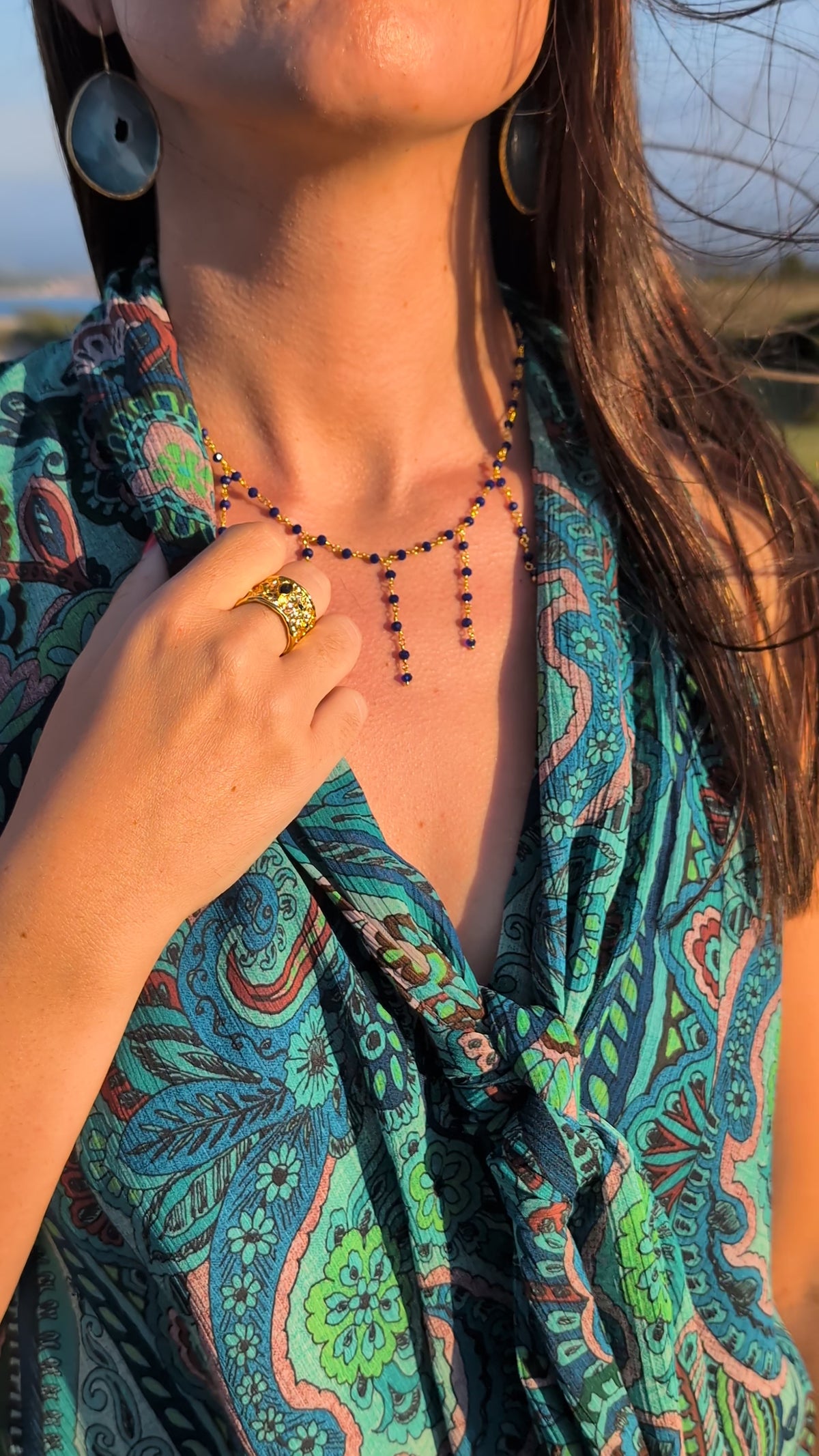 Video de modelo en la costa del Norte luciendo collar de piedras con flecos, anillo dorado y pendientes de AMANAI.